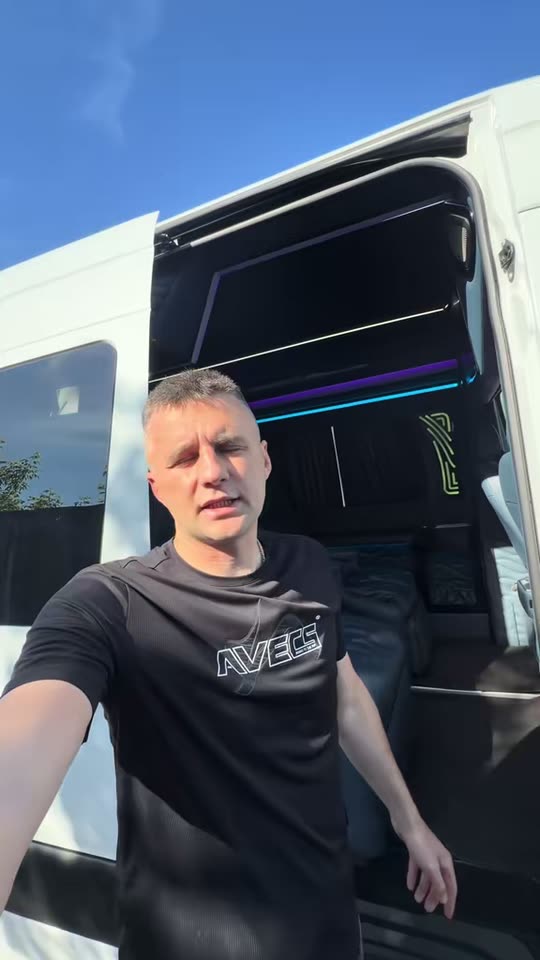 Чоловік біля відчинених дверей буса, за ним салон з підсвічуванням